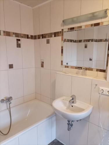 a white bathroom with a sink and a bath tub at Hotel An der Karlstadt in Bremerhaven