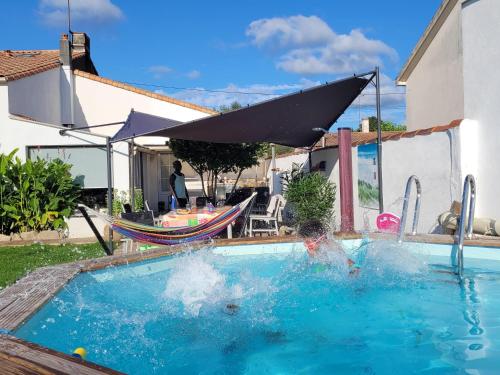 un enfant jouant dans une piscine avec un parasol dans l'établissement La genotière, à Mouilleron-le-Captif