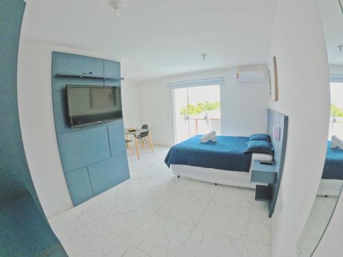 1 dormitorio con 1 cama y TV en una habitación en Makaha Exclusive Suítes en Praia do Rosa