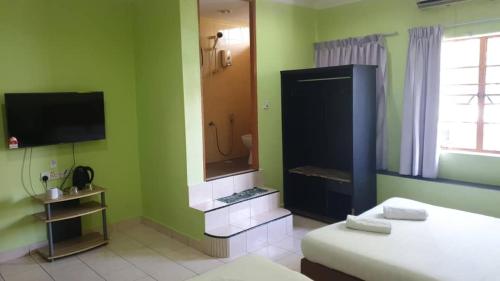 1 dormitorio con 1 cama y baño con TV. en Borneo Gaya Lodge, en Kota Kinabalu