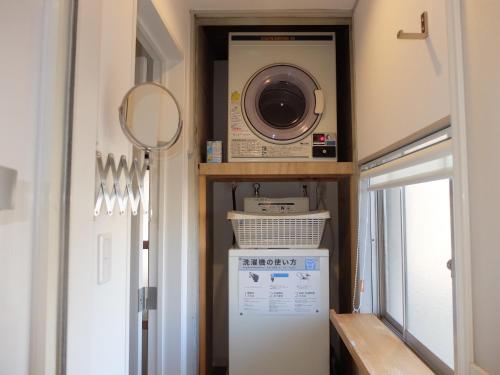 a laundry room with a microwave and a refrigerator at Kitazawa Cozy House in Tokyo