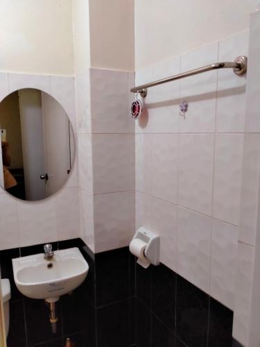 a white bathroom with a sink and a mirror at V.F. Riton Apartelle in Laoag