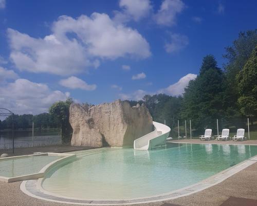 - une piscine avec toboggan en face d'un rocher dans l'établissement Chalet simple au Camping L'Etruyere au lac, à La Tardière