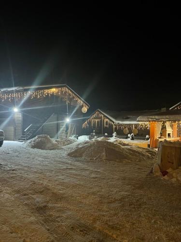 a house covered in snow at night with lights at Карпатська Криївка in Yasinya