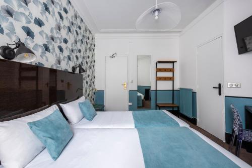 a bedroom with a large white bed with blue pillows at Lennon by Avalon Hotel Paris Gare du Nord in Paris