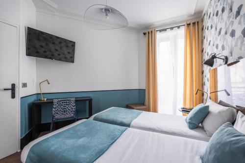 a bedroom with two beds and a tv on the wall at Lennon by Avalon Hotel Paris Gare du Nord in Paris