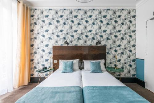 a bedroom with a large bed with blue pillows at Lennon by Avalon Hotel Paris Gare du Nord in Paris
