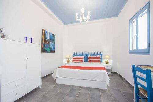 a white bedroom with a bed with red and blue pillows at Jasmine Suites Poolhouse Rhodos in Koskinou