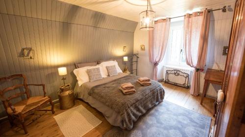 a bedroom with a bed and a chair and a window at Ferme des Prades in Landeyrat