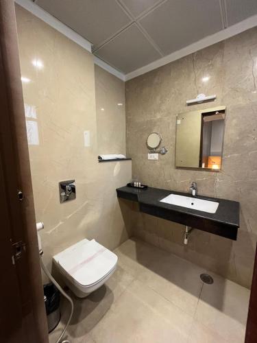 a bathroom with a toilet and a sink and a mirror at Hotel Sarvin in Lucknow