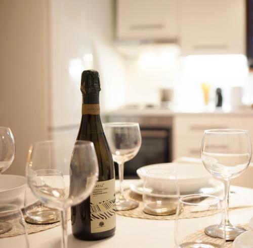 una bottiglia di vino appoggiata su un tavolo con bicchieri da vino di Domina Trastevere Apartment - Roma a Roma