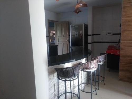 a kitchen with a bar with stools and a refrigerator at Casa para temporada Florianópolis in Florianópolis