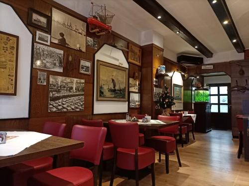 a dining room with tables and red chairs at Hotel An der Karlstadt in Bremerhaven