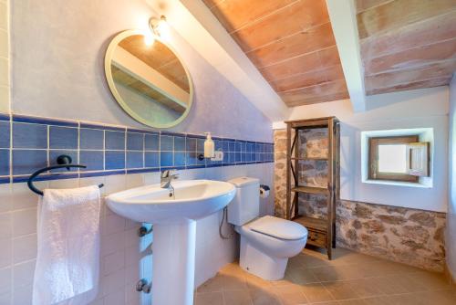 a bathroom with a sink and a toilet and a mirror at Finca Es Casal by Mallorca House Rent in Sant Llorenç des Cardassar