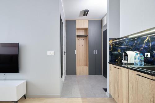 a kitchen with white cabinets and a tv and a counter at Green Ande in Wrocław
