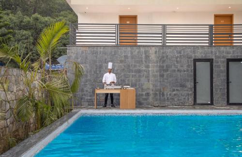 een man die aan een bureau naast een zwembad zit bij TRIBHAV Corbett Bliss-Jim Corbett in Rāmnagar