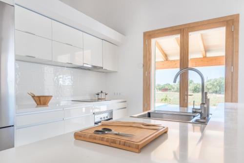 a white kitchen with a cutting board on the counter at Finca Sa Vinya by Mallorca House Rent in Felanitx