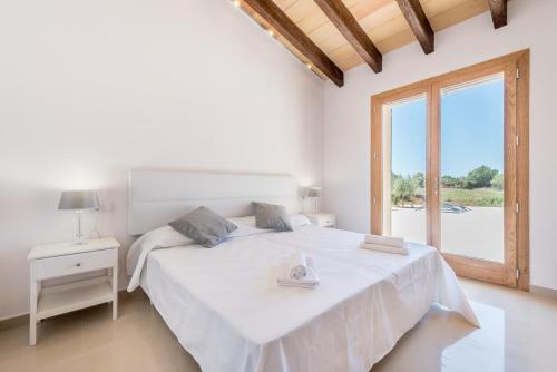 a white bedroom with a large bed and a window at Finca Sa Vinya by Mallorca House Rent in Felanitx