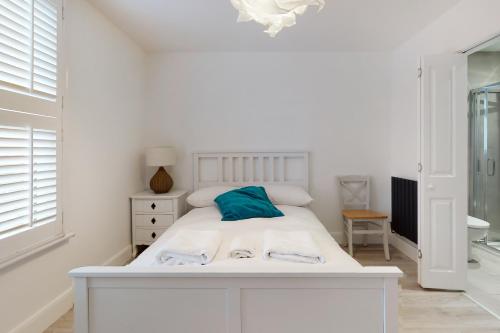 a white bedroom with a white bed with a blue pillow at Beautiful 3 bed house 30 mins from Central London in Kingston upon Thames