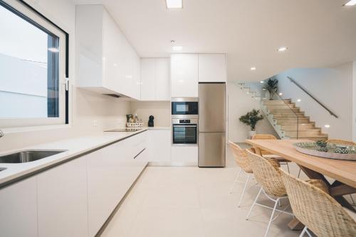 a kitchen with white cabinets and a wooden table at Villa Sofia Atlantica in Lourinhã