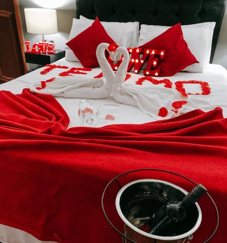 two white swans sitting on a bed with red sheets at Pousada Vale Valparaíso Inn- Polo gastronômico in Petrópolis