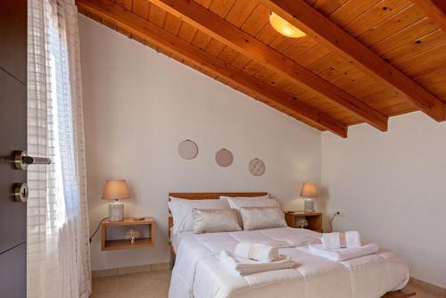 a bedroom with a large white bed and wooden ceilings at Villa Ellovos with Private Pool in Rethymno Town