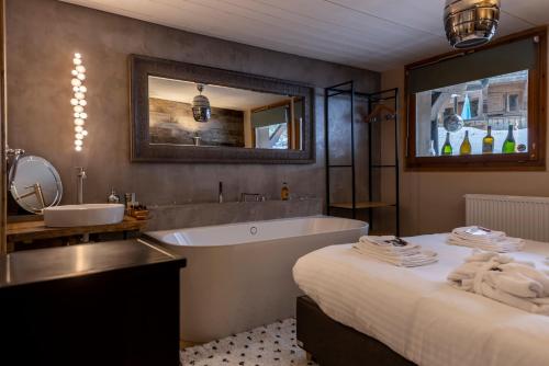 uma casa de banho com uma banheira, uma cama e um lavatório. em Hôtel et Chalet Au Coin Du Feu Chilly Powder em Morzine