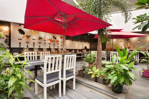 a restaurant with a red umbrella and chairs and plants at Days Inn & Suites by Wyndham Bengaluru Whitefield in Bengaluru