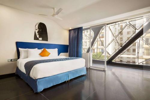 a bedroom with a blue bed and a large window at Days Inn & Suites by Wyndham Bengaluru Whitefield in Bangalore