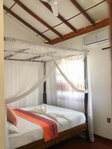ウェリガマにあるThe Sea View Villa Surf Schoolのベッドルーム1室(天蓋付きベッド1台、窓付)