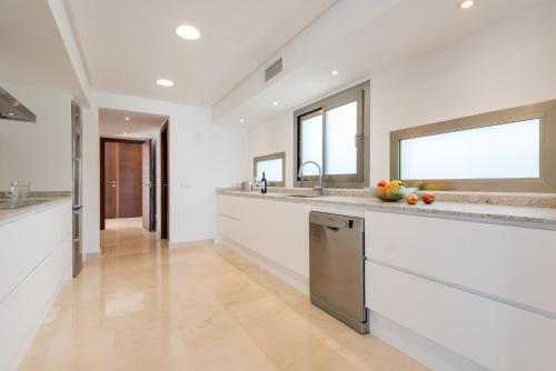a large kitchen with white walls and stainless steel appliances at Villa Es Falcons in Porto Cristo