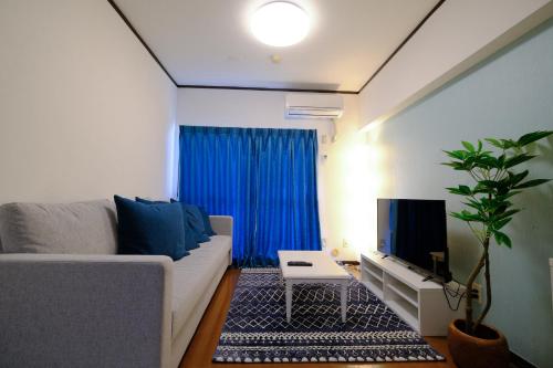 a living room with a couch and a tv at ケイアイコンホテルズ 池下 in Chikusachō