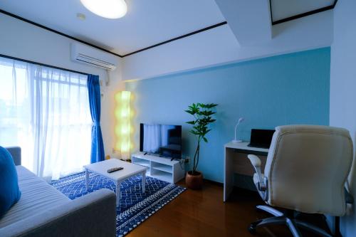 a living room with a couch and a desk with a computer at ケイアイコンホテルズ 池下 in Chikusachō