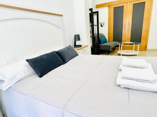 Una cama blanca con almohadas azules encima. en Be Suites Centro, en Granada