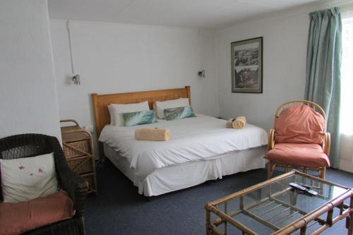 a bedroom with a bed and a chair at Absolute Leisure Cottages in Machadodorp