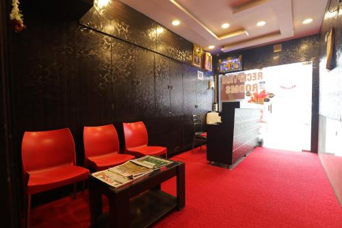 a waiting room with red chairs and a table at Udupi Residency in Bengaluru