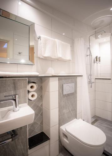 a white bathroom with a toilet and a sink at Hotel Oscar in Amsterdam