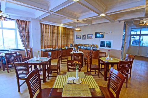 restauracja ze stołami i krzesłami w pokoju w obiekcie Royal Pearl Hotel w mieście Mandalaj
