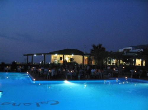 una gran piscina azul por la noche con un grupo de personas en Villaggio Hotel Club Calanovellamare, en Piraino