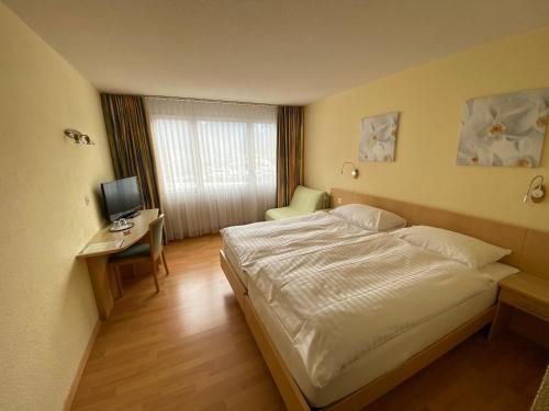 a bedroom with a bed and a desk and a television at Hotel Sherlock Holmes & Khana Restaurant "200 m Gondola to Hasliberg ski" in Meiringen