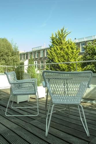 two chairs sitting on top of a deck at Hotel The Neighbour's Magnolia in Amsterdam