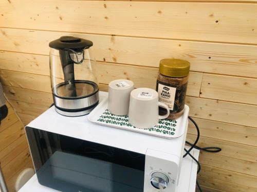 a counter with two coffee cups on top of a microwave at Niiralan Tila : Skyview Cabin in Pahajoki