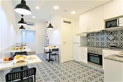 une cuisine avec des placards blancs et une table avec de la nourriture. dans l'établissement Suites Amália Guesthouse near Rossio Square, à Lisbonne