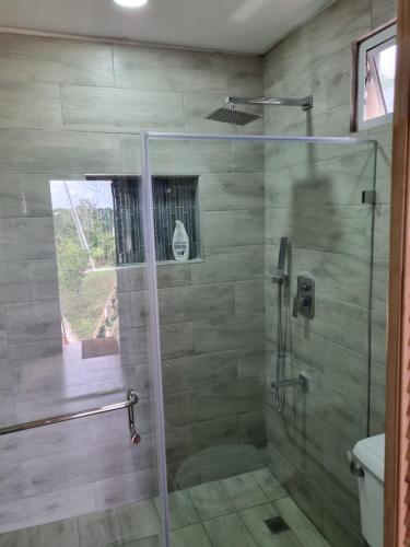 a bathroom with a shower with a glass door at Trésor Caché TT in Claxton Bay