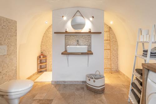 a bathroom with a white toilet and a sink at Écrin de Nature en bord de rivière in Cenans