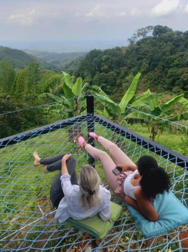 three girls laying on a net on a zip line at Cristal House Glamping at Villa Migelita Ecolodge in Palmira