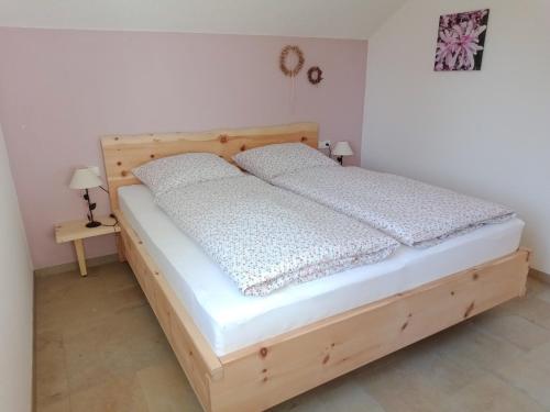 1 dormitorio con cama de madera con sábanas blancas en Haus Sonnentau Wohnung 2, en Kisslegg
