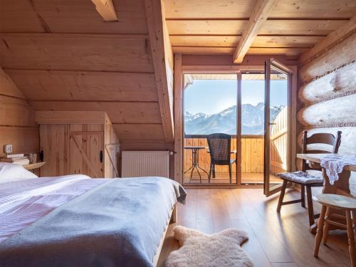 a bedroom with a bed and a balcony with mountains at Dom Tatrzański Ewa II in Kościelisko