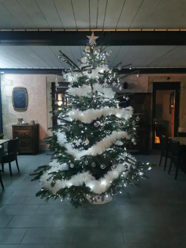 Un arbre de Noël avec de la neige dans une pièce dans l'établissement Le P'tit Bouchon, à Rambervillers