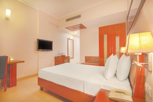 a bedroom with a bed and a desk with a telephone at Lemon Tree Hotel Baddi in Baddi